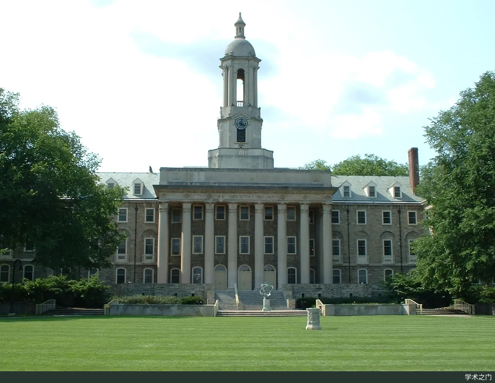 A summer exterior view of the Old Main administration building on Pennsylvania State University's University Park campus, with a lawn and green trees in front of the clock tower