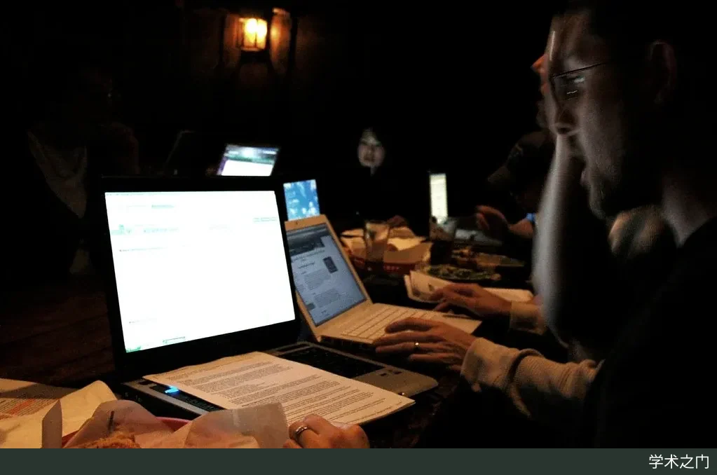 Members of a graduate study group at the University of Washington Information School sit around a table, studying and discussing together in front of a laptop screen
